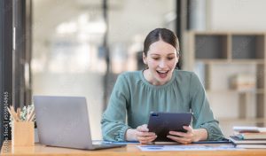 Excited Canada American woman sit at desk feel euphoric win online lottery, happy black woman overjoyed get mail at tablet being promoted at work, biracial girl amazed read good news at computer