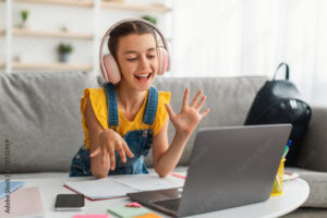 Smiling girl in headset using laptop, talking during videochat