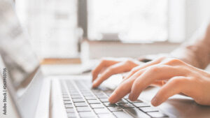 Distance education. Online college training. Remote student learning. Closeup of hands typing on laptop.