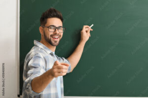 Male teacher writing on blackboard in classroom