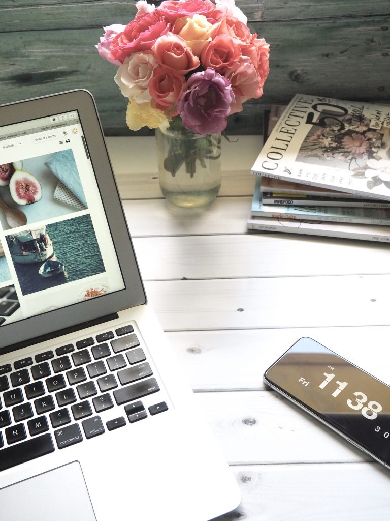 Macbook air flower bouquet and magazines on white table