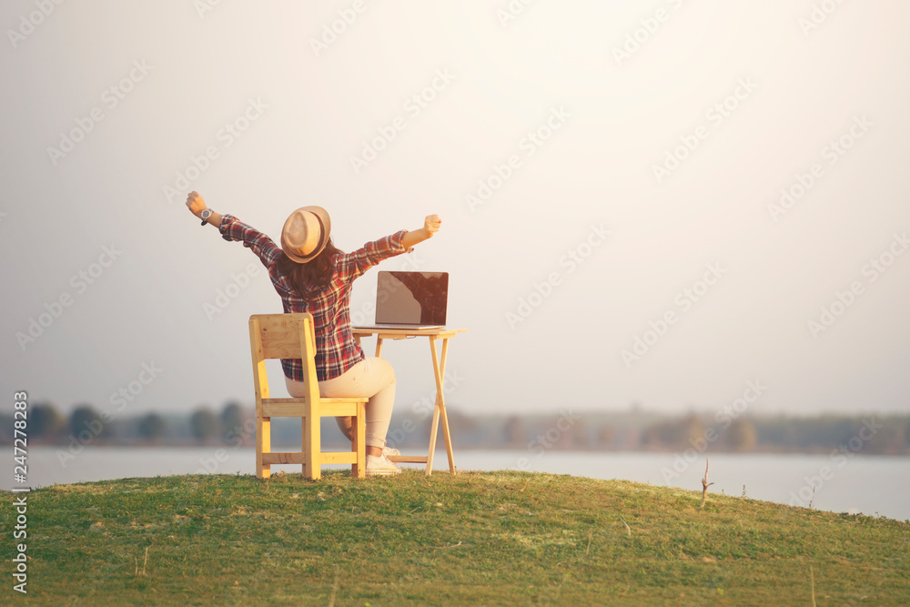 Woman using laptop with open arm in nature background