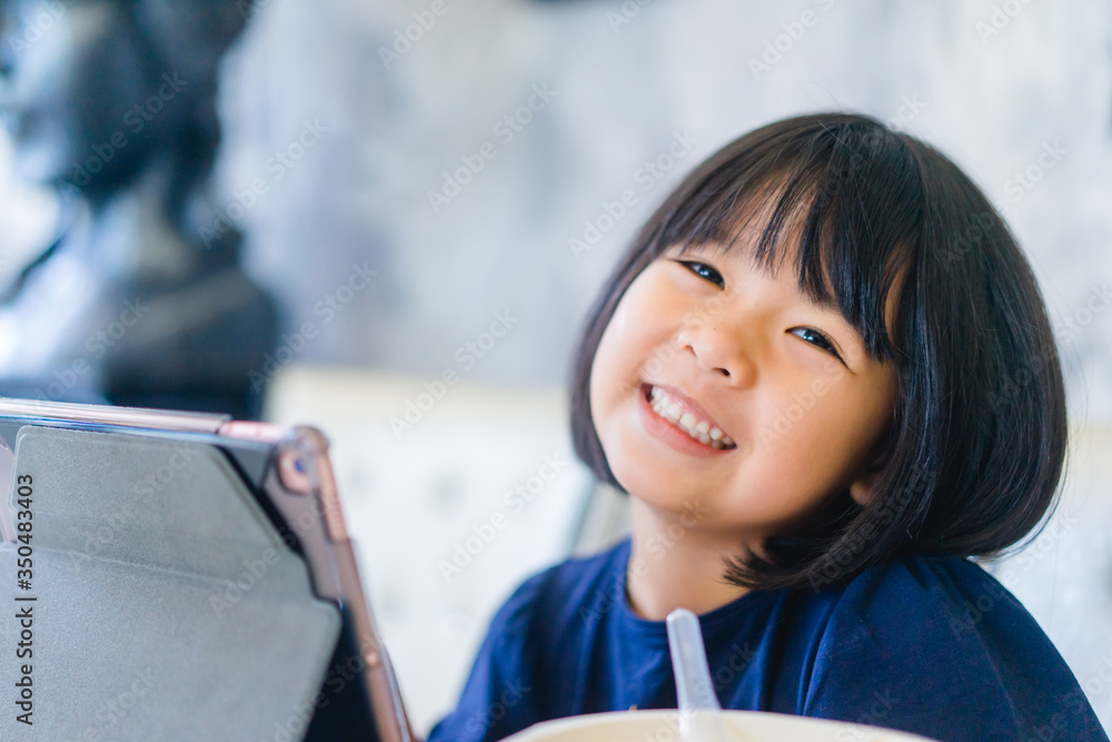 Asian girl student online learning in class study.Online video call with teacher.Child girl eating rice congee breakfast with laptop at home.New normal.Covid-19 coronavirus.Social distancing.stay home