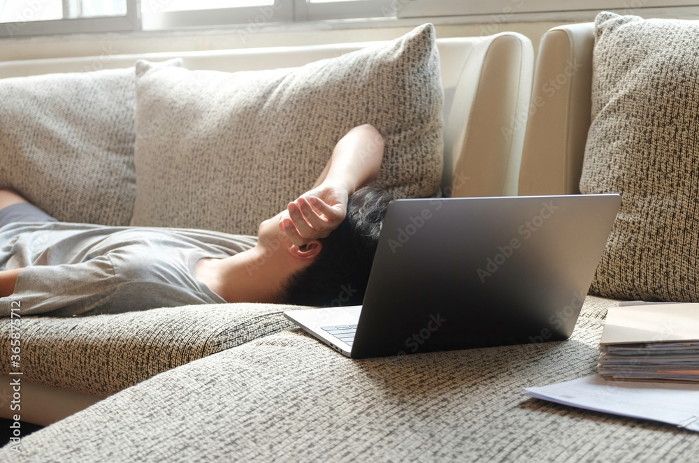 Asian man sleeping while working form home on sofa