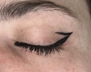 Close up of closed eye. Black liner along the upper lash line making a wing. small line starting at end of wing, going a little into the lid. 