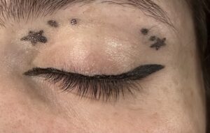 Close up of closed eye. Small black winged liner. star on the outer corner with two dots going into the eye. star on inner corner with two dots going into the eye.