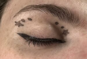 Close up of closed eye. Small black winged liner. star on the outer corner with two dots going into the eye. star on inner corner with two dots going into the eye.