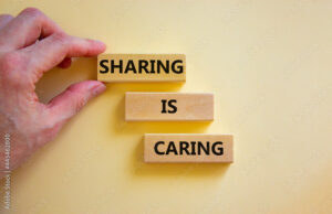 Sharing is caring symbol. Wooden blocks with words 'Sharing is caring' on beautiful white background. Businessman hand. Business, sharing is caring concept. Copy space.