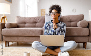 Thoughtful dreaming ethnic woman doing paperwork at home