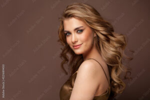 Beautiful glamorous model woman with long wavy and shiny hair against brown studio wall banner background