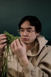 Man holding a tangled green yarn