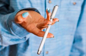 Cropped image of woman in blue shirt Hold pen in your hand. pen spinning