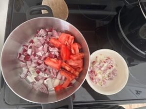 Chopped white onion, purple onion, and tomatoes in a pot.