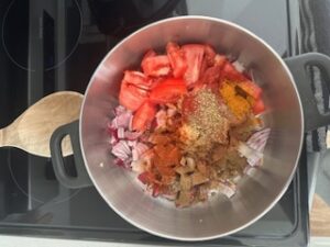 Chopped vegetables and spices in pot.