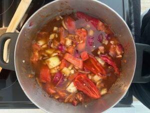 Vegetables cooking with beef stock in pot.