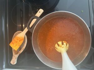 Immersion blending cooked vegetables in pot.