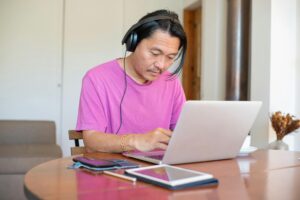 Man wearing headset typing on his laptop