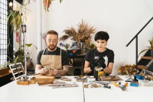 Man in black shirt and brown apron sitting beside a woman in black shirt