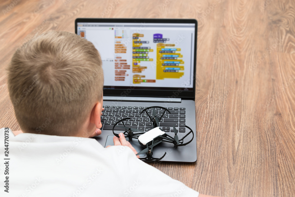 A teenage boy programs a copter drone on a scratch. STEM education. Modern technology and gadgets.