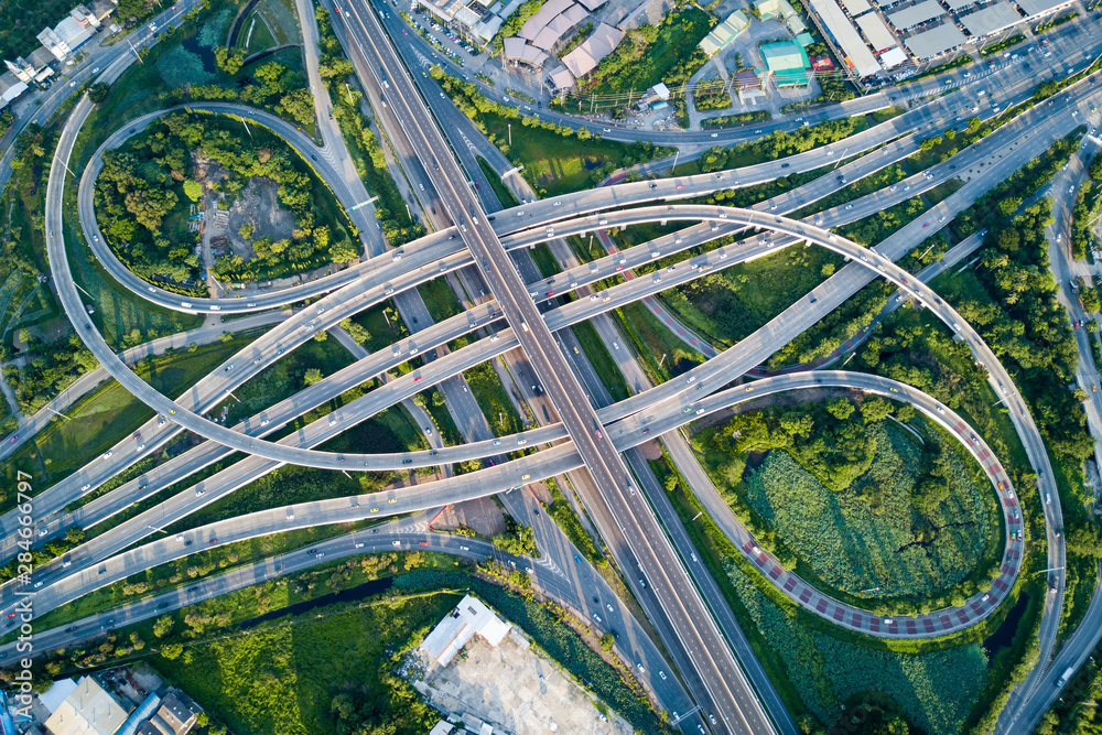 Aerial view of road interchange or highway intersection with busy urban traffic speeding on the road. Junction network of transportation taken by drone.