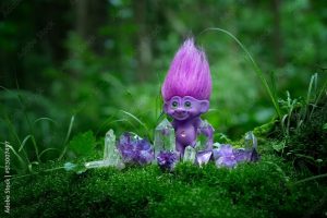 tale troll with crystals in forest, natural green background. troll toy with ruffled violet hair in mystery forest, symbol of fairytale.