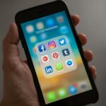 Person holding iphone showing social networks folder.