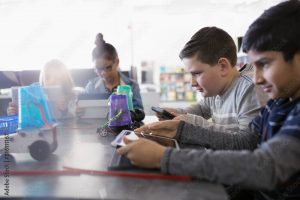 Pre-adolescent boys programming robotics at digital tablets in classroom