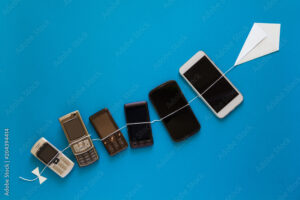Technology evolution concept. Vintage and new phones flying on paper kite on blue sky. Origami. Paper cut. Top view