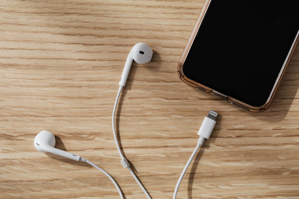 Smartphone with white earphones on wooden table