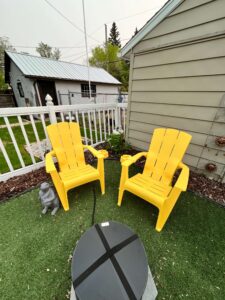 Firepit with two yellow chairs and a planted hydrangea bush