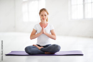 woman practicing yoga and meditating in lotus position