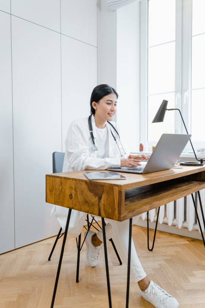 Woman in white dress shirt sitting on chair using macbook