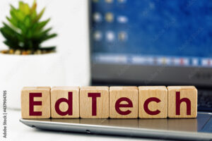 photo on EdTech theme. wooden cubes with the words "EdTech", on the background of laptop and succulent