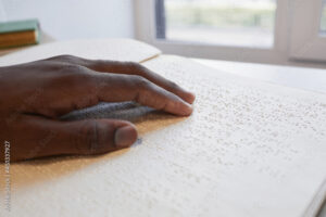 Close up of African-American hand reading braille book for blind, copy space