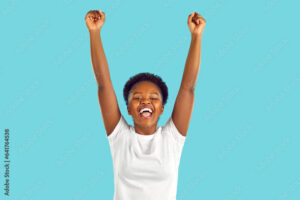 Happy woman celebrating success. Ecstatic competition winner celebrating victory. Studio shot of excited young African American girl in casual top raising her hands up and shouting Hurray, I did it