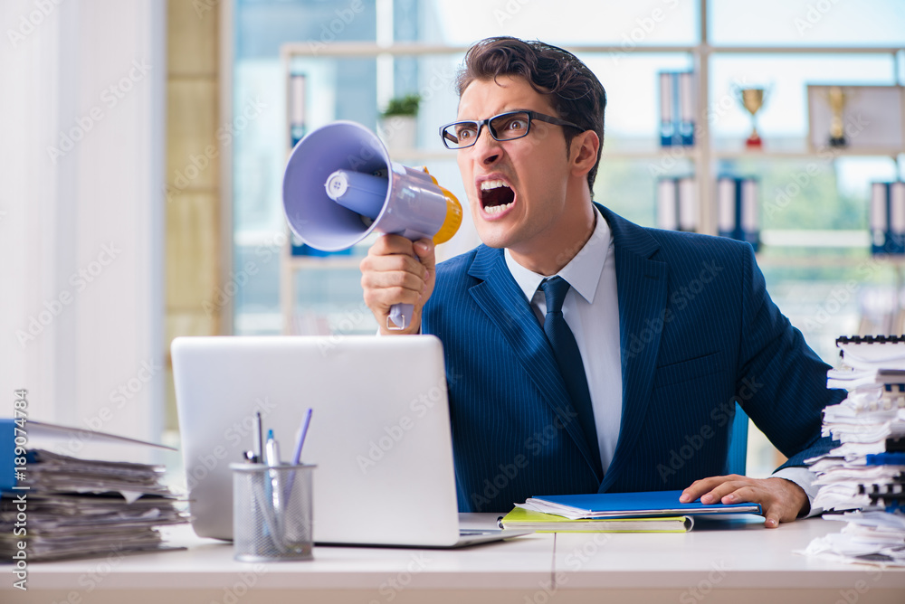 Angry aggressive businessman with bullhorn loudspeaker in office