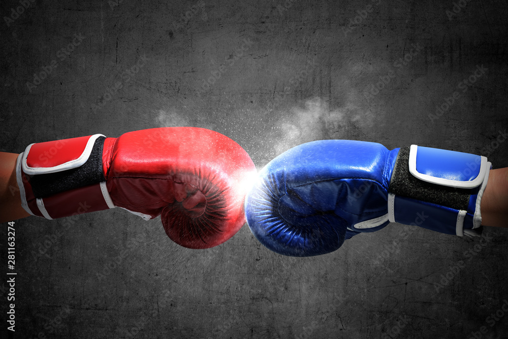 Hands of two men with blue and red boxing gloves bumped their fists