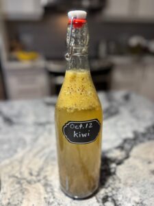 A bottle of kiwi kombucha on a kitchen counter.