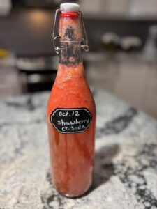 A bottle of Strawberry Cream Soda Kombucha on a kitchen counter.