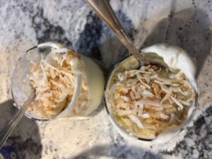 An photograph of two glasses of a matcha, kombucha float with ice cream and toasted coconut on top.