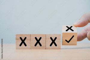 Hand flipping wooden cube block to change cross incorrect to correct mark.