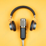 podcasting concept, directly above view of headphones and recording microphone on orange background