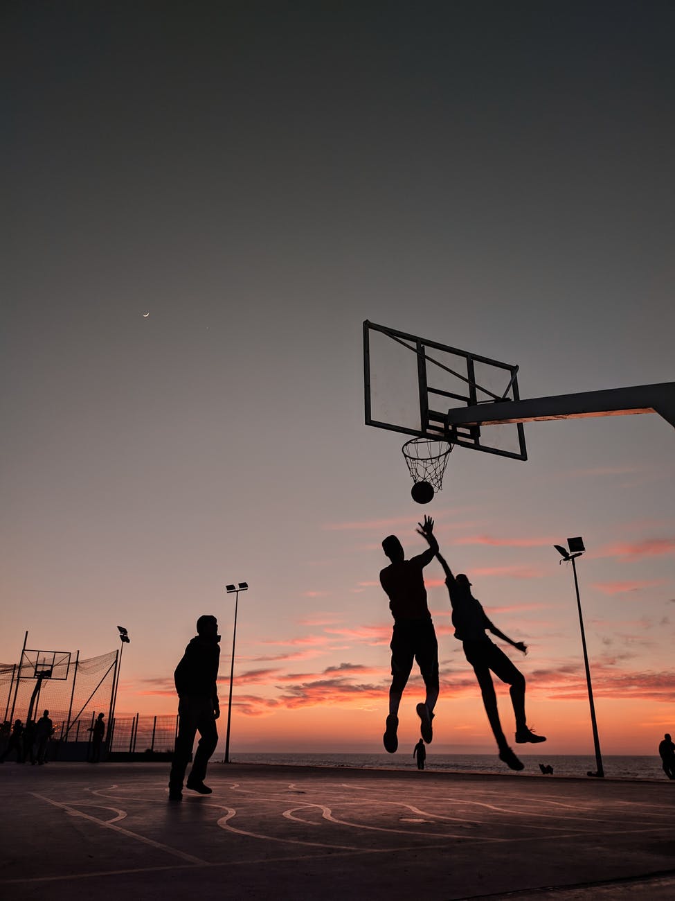 silhouette of people playing basketball during sunset