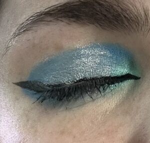 Close up of closed eye. Black wing liner, which blue eyeshadow and silver shimmer.