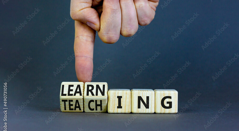 Learning or teaching symbol. Businessman turns wooden cubes and changes the word Teaching to Learning. Beautiful grey table grey background. Educational learning or teaching concept. Copy space.