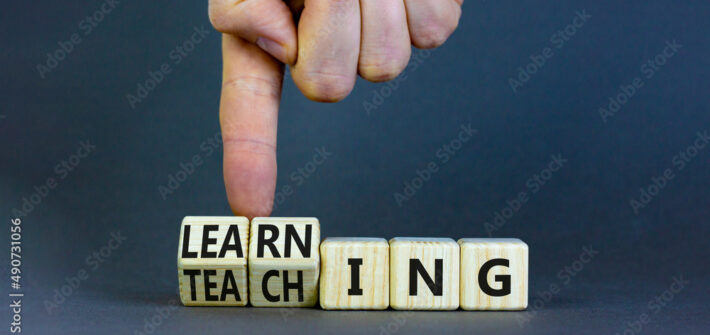 Learning or teaching symbol. Businessman turns wooden cubes and changes the word Teaching to Learning. Beautiful grey table grey background. Educational learning or teaching concept. Copy space.
