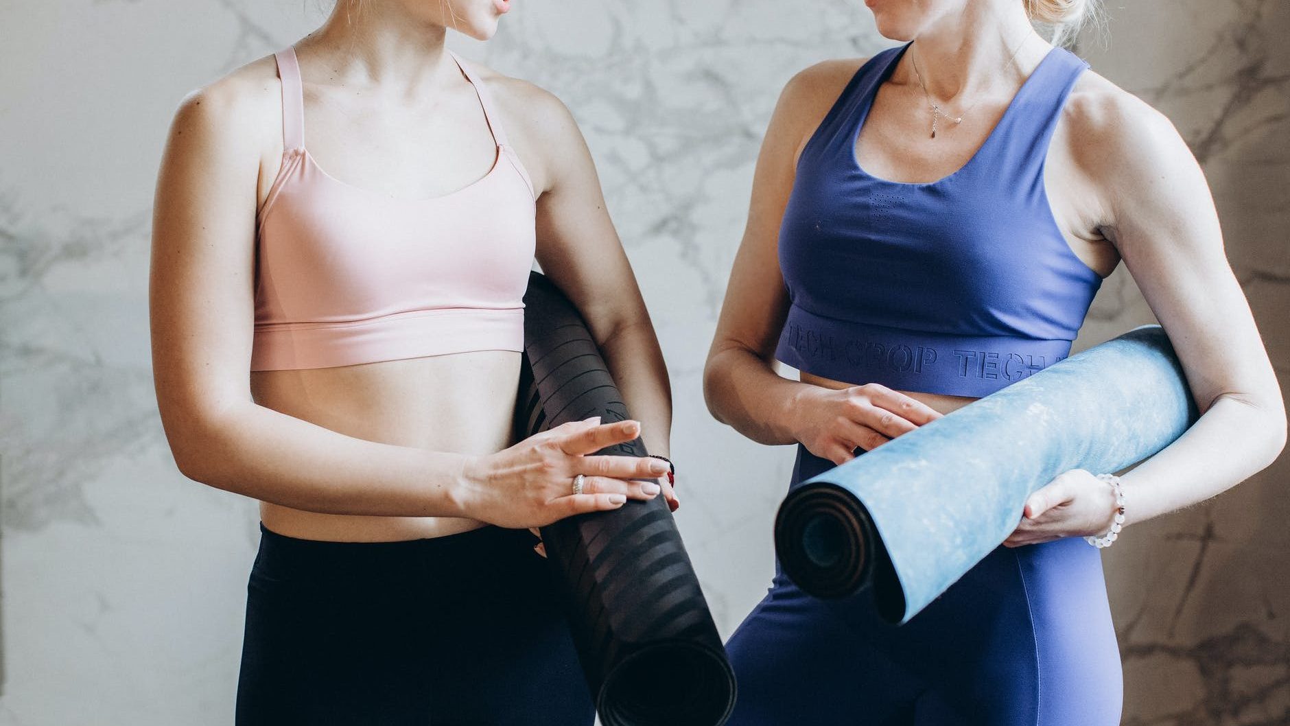 women with yoga mats talking