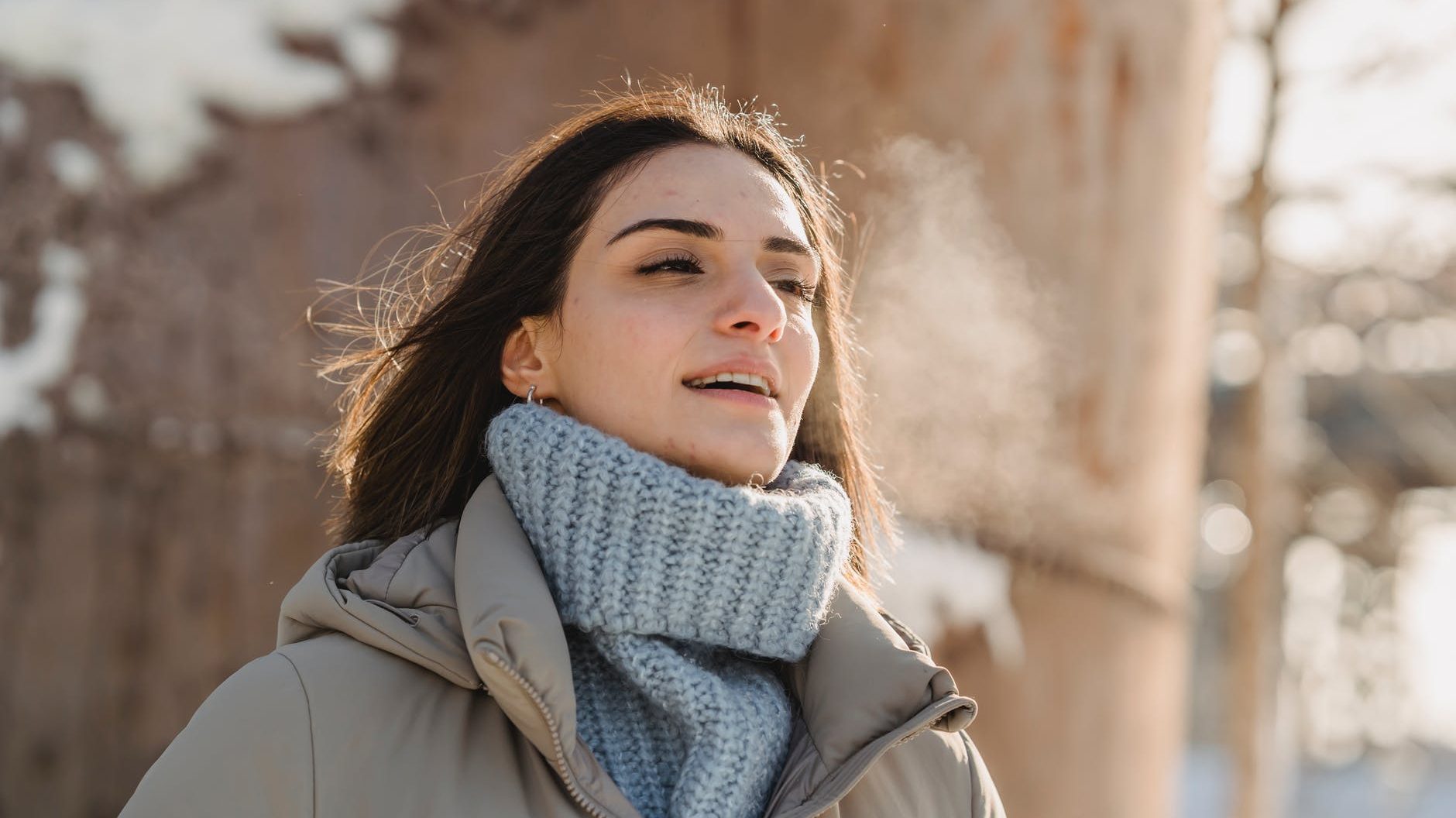 young woman exhaling steam on freezing cold weather
