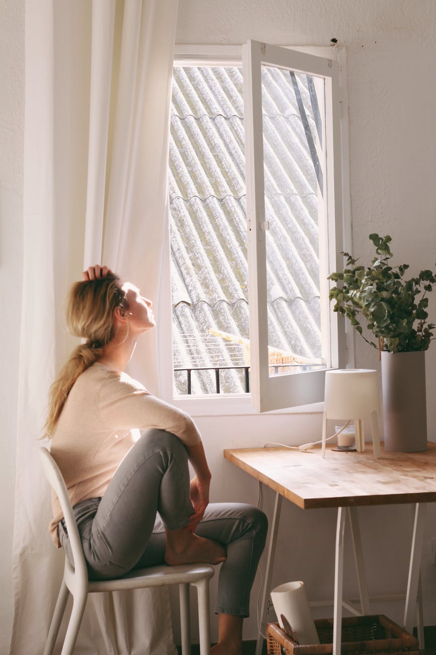 woman sitting on a chair next to a window