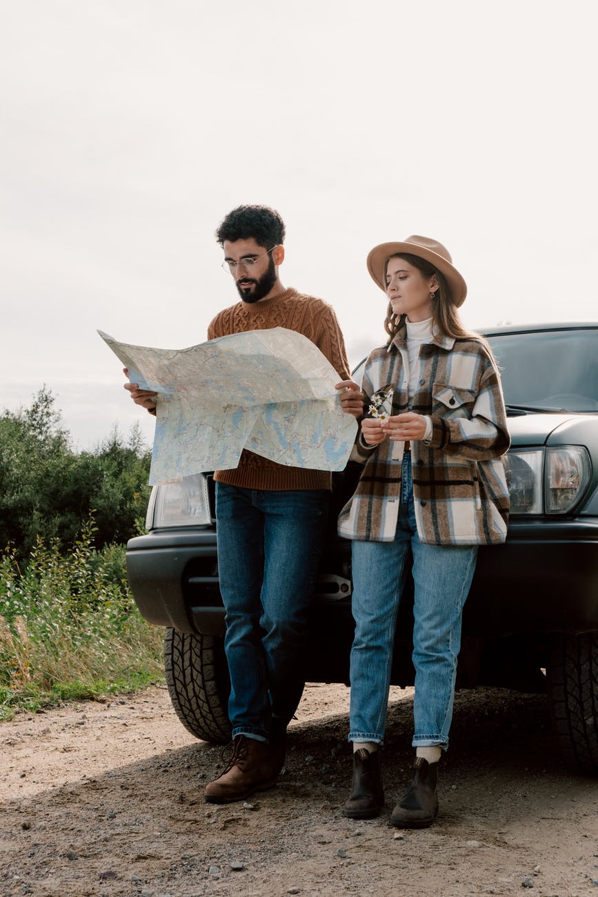 man and woman standing beside car